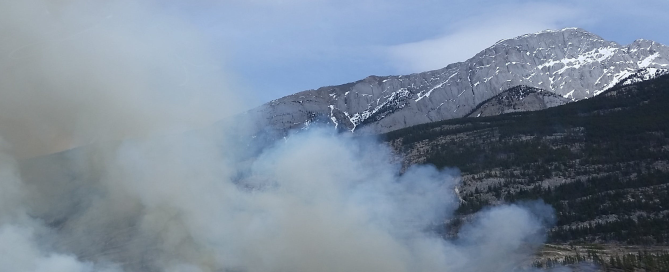 Smoke in front of a mountain in a field